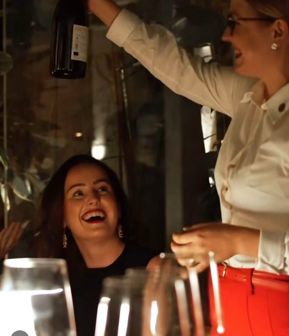 Anastasiia presenting a bottle of wine to a delighted guest at a Sip Royal evening