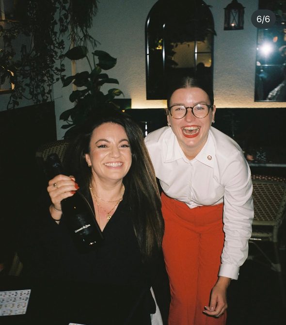 Anastasiia laughing with a delighted guest holding a bottle of wine