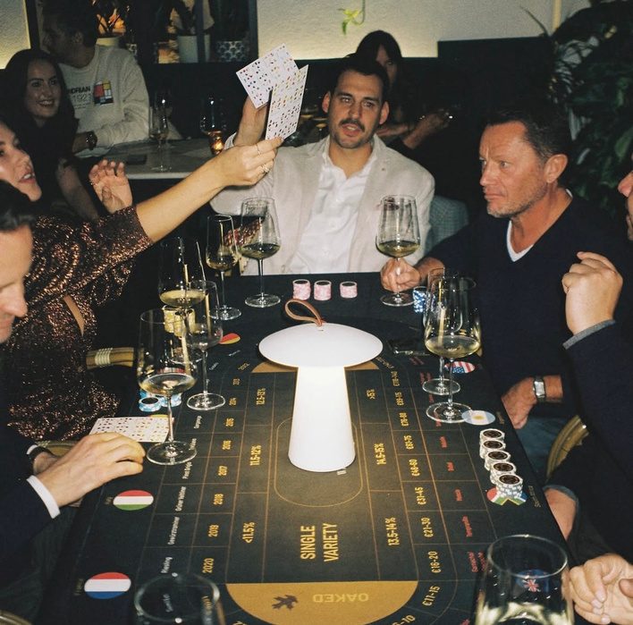 Guests playing at the black-and-gold Sip Royal table with wine glasses and country flags
