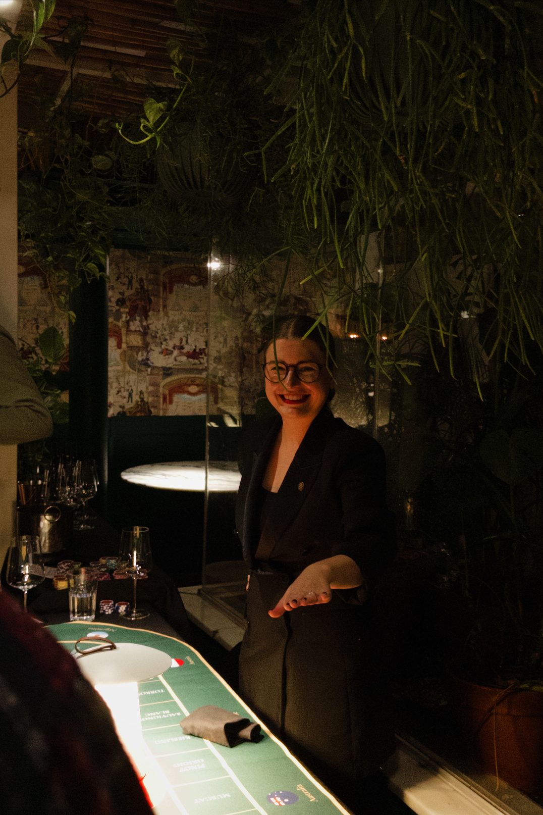 Anastasiia smiling and holding betting chips beside the green Sip Royal game table